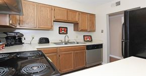 Winston-Salem apartment for rent - A kitchen with a black stove top oven and wooden cabinets.