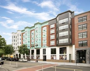 Jersey City apartment for rent - A street view of a city with cars parked and buildings in the background.