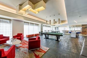 Washington apartment for rent - A modern living room with red chairs and a pool table.