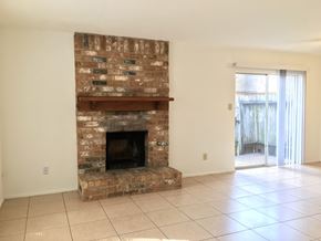 Conroe apartment for rent - the living room has a brick fireplace and a tile floor