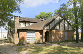 Conroe apartment for rent - the front of a brick house with a garage and trees