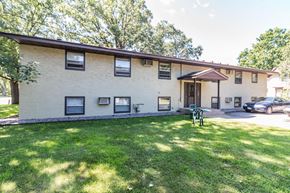 Princeton apartment for rent - the front of a white building with a green lawn and a car parked in front
