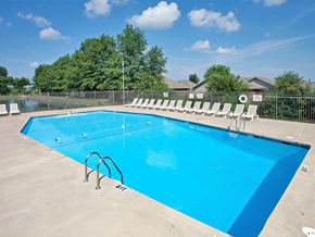 Siloam Springs apartment for rent - a swimming pool with white chairs around it and trees in the background