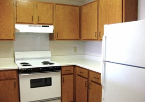 Flushing townhouse for rent - a kitchen with white appliances and wooden cabinets