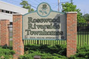 Flint townhouse for rent - a sign for rosewood riverside townhomes in front of a fence