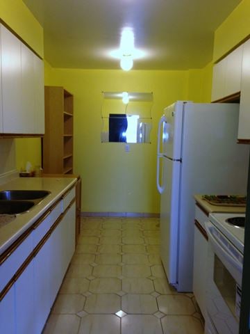 Toronto apartment for rent - A kitchen with a white refrigerator and a black sink.