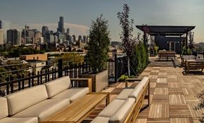 Chicago apartment for rent - a rooftop patio with couches and tables and a city in the background