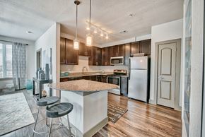 Conroe apartment for rent - a kitchen with an island with stools and a refrigerator