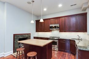 Philadelphia apartment for rent - a kitchen with wooden cabinets and an island with three stools