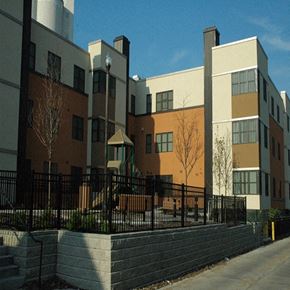 Minneapolis apartment for rent - A black fence surrounds a building with a mix of beige and brown colors.