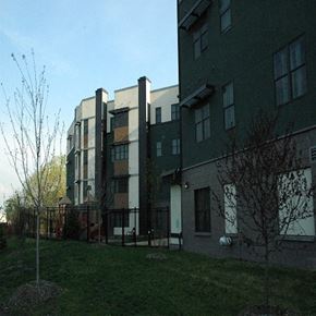 Minneapolis apartment for rent - A building with a green fence and a tree in front of it.