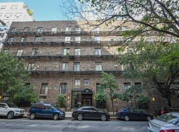Manhattan triplex for rent - a large brick building with cars parked in front of it