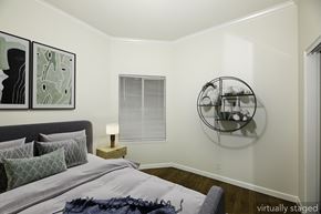 San Francisco apartment for rent - A bedroom with a bed, pillows, a nightstand, a window with blinds, and a wall-mounted shelf with cups and a vase.