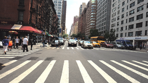 New York apartment for rent - a busy city street with cars and pedestrians on a crosswalk