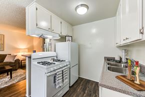 Van Nuys apartment for rent - Open concept kitchen with gas range, fridge, and plank flooring at the Promenade Apartment in Van Nuys, CA