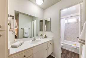 Sherman Oaks apartment for rent - A bathroom with a large vanity with ample storage, large mirror, a bathtub, and plank flooring at the Windsor Apartment in Sherman Oaks