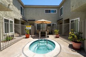 Tarzana apartment for rent - a small pool is in the middle of a patio with a fence and a building