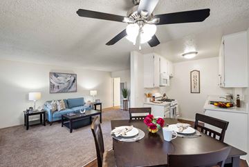 Van Nuys apartment for rent - A dining room with a table set for two and a living room with a couch and lamp in the background.