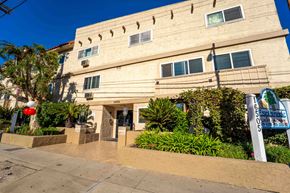 Van Nuys apartment for rent - The exterior of The Esplanade with lush landscaping, a tiled entryway, and a prominent property sign.
