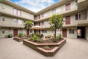 Sherman Oaks apartment for rent - Beautifully manicured courtyard at the Hallmark Apartments in Studio City, showcasing the trees, a sitting area, and in the background are the apartment homes and the leasing office.