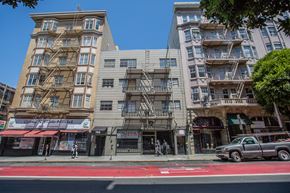 San Francisco apartment for rent - A street view of a city with buildings, a pedestrian, and a car.