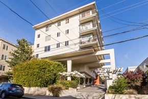 San Francisco apartment for rent - A modern white apartment building with balconies and a car parked in front.