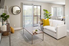 Omaha apartment for rent - A living room with a white couch, a coffee table, and a mirror on the wall.