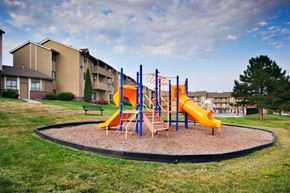 Omaha apartment for rent - A playground with a yellow slide and a blue and orange climbing frame.