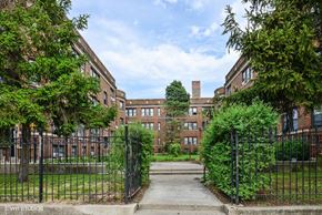 Chicago apartment for rent - the courtyard of a large brick building with trees and a fence
