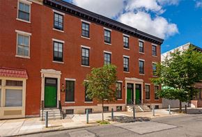 Philadelphia townhouse for rent - a red brick building with green doors on a street