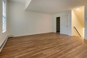 Philadelphia townhouse for rent - the living room and dining room of an empty house with wood flooring