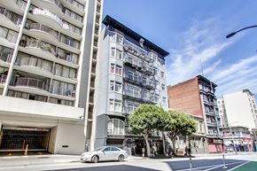 San Francisco apartment for rent - A white car is parked on the side of a street in front of a tall building.