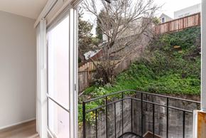 San Francisco apartment for rent - A balcony with a black railing and a view of a green hillside.