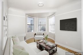 San Francisco apartment for rent - A living room with a couch, a chair, a coffee table, and a flat screen TV mounted on the wall.