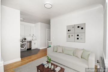 San Francisco apartment for rent - A white couch with green pillows sits in a living room with a wooden coffee table in front of it.