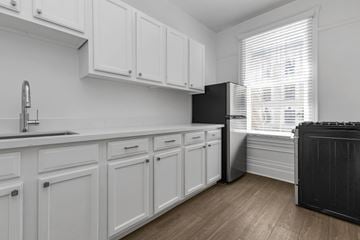 San Francisco apartment for rent - A black refrigerator is in a kitchen with white cabinets.