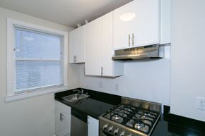 San Francisco apartment for rent - A kitchen with white cabinets and a black countertop.