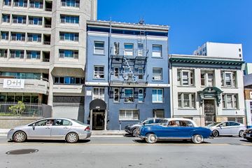 San Francisco apartment for rent - A blue car is parked in front of a blue building with a fire escape.