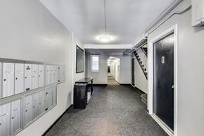 San Francisco apartment for rent - A long hallway with a black door on the right and a staircase on the left.