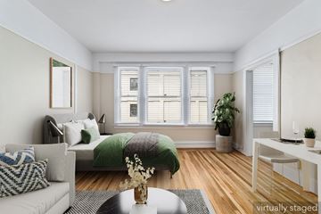 San Francisco apartment for rent - A living room with a couch, a bed, and a table with a vase of flowers on it.