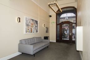 San Francisco apartment for rent - A grey sofa sits in a room with a framed picture on the wall and a door with a sign that says "EXIT" above it.