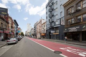 San Francisco apartment for rent - A street with a red bike lane and a sign that says "Hertz" on the side of a building.