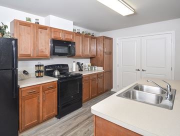Tiffin apartment for rent - A kitchen with wooden cabinets and black appliances.