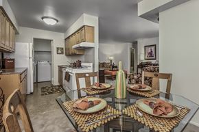 Millville apartment for rent - A dining table set with plates and napkins is in the foreground of a kitchen.
