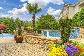 Charlotte apartment for rent - a backyard with a pool and flowers and a stone retaining wall