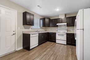 Rocky Mount apartment for rent - a kitchen with dark wood cabinets and white appliances