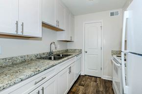 Nashville apartment for rent - a kitchen with white cabinets and a sink and a refrigerator