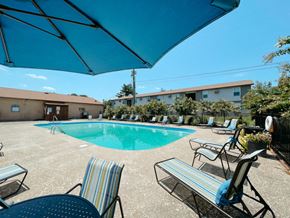 Clarksville apartment for rent - our resort style swimming pool is next to our building with chairs and a blue umbrella