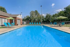 Columbia apartment for rent - a swimming pool with blue chairs and umbrellas next to a brick building