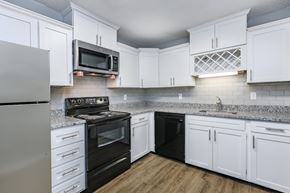 Knoxville apartment for rent - A kitchen with white cabinets and black appliances.